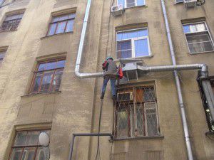 grimpeur monte une unité de ventilation à l'extérieur du bâtiment